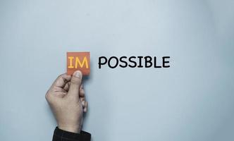 mano che tiene carta rossa e alfabeto im da aggiungere per il cambiamento possibile, idea di pensiero positivo e concetto di mentalità impossibile. foto