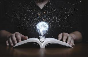 lampadina incandescente con cervello virtuale su libro aperto e linea di connessione per la lettura e l'istruzione rendono il concetto di idea di pensiero intelligente o creativo. foto