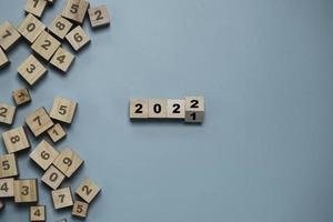 capovolgimento di un blocco cubo di legno per il cambiamento dal 2021 al 2022 con altri numeri su blocchi su sfondo blu per buon natale e felice anno nuovo, avviare nuovi affari e concetto di piano.