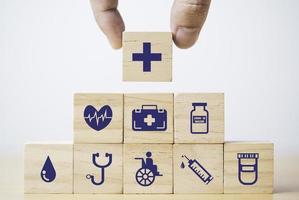 mettere e impilare a mano icone mediche e sanitarie che stampano lo schermo su un blocco cubo di legno per il concetto di assicurazione sanitaria. foto