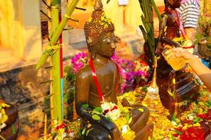 innaffiare statue di buddha con acqua profumata e petali di fiori il capodanno laotiano foto