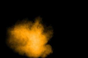 esplosione astratta di polvere arancione su sfondo nero. congelare il movimento di schizzi di polvere arancione. foto