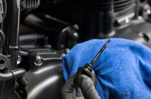 meccanico controlla il livello dell'olio motore su una grande motocicletta in garage. Concetto di riparazione, manutenzione e servizio della moto foto