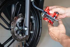 il meccanico sostituisce e regola l'impianto frenante della motocicletta in garage. Manutenzione, riparazione del concetto di motocicletta. Messa a fuoco selettiva foto
