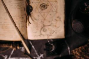 apri il vecchio libro con incantesimi, rune, candele nere sul tavolo delle streghe. concetto occulto, esoterico, divinatorio e wicca. foto