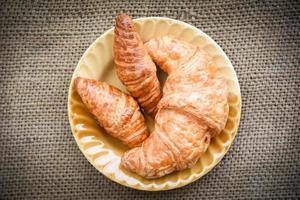 croissant al forno - pane da forno sul sacco nella tavola concetto di cibo per la colazione fatta in casa foto