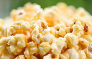 primo piano popcorn in tazza e natura verde backgroubd - sale per popcorn al burro dolce foto