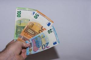 tre banconote in euro tenute in una mano con il grigio foto