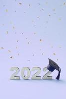 laurea 2022 con cappello laureato su un numero 2022 di legno su sfondo colorato molto filettato con coriandoli volanti foto