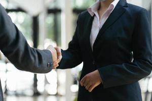 donne d'affari che si stringono la mano, soddisfatte del lavoro, la donna che si sta divertendo con il suo compagno di lavoro, stretta di mano che fa gesti con le persone concetto di affare di connessione foto