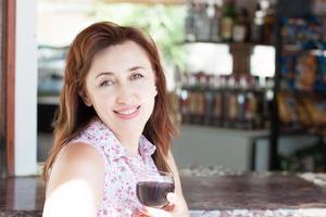 felice donna di mezza età tenere un bicchiere di vino rosso nel bar dell'hotel foto