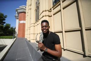 uomo afroamericano che si diverte a camminare nel centro della città - giovane ragazzo felice che si gode il tempo al tramonto all'aperto - stile di vita della generazione millenaria e concetto di atteggiamento positivo delle persone foto