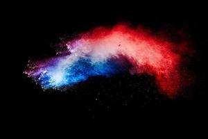 esplosione di particelle di polvere blu rossa su sfondo nero. spruzzata di polvere blu rossa. foto
