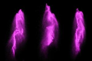 le particelle rosa schizzano su sfondo nero. esplosione di polvere rosa. foto