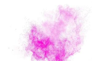 le particelle di polvere rosa spruzzano su sfondo bianco. foto