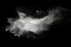 nubi di esplosione di polvere bianca. congelare il movimento di schizzi di particelle di polvere bianca su sfondo nero. foto