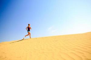 donna felice che corre jogging sulle dune di sabbia foto