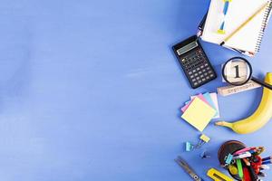 materiale scolastico diverso su sfondo blu. concetto di ritorno a scuola foto