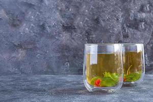 tazza di vetro con tè verde ai frutti di bosco e menta. foto
