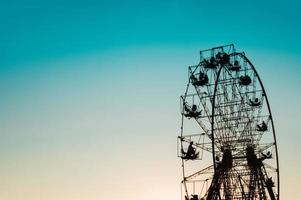 sagoma della ruota panoramica contro il cielo blu chiaro e arancione foto