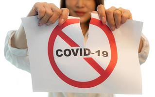 donna che tiene e strappa la carta con le parole di avvertimento del coronavirus covid-19. l'idea o il concetto per il finale, felicità e libera dopo aver terminato e recuperato dal coronarivus, su sfondo bianco foto