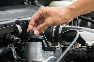 un meccanico sta aprendo il tappo dell'olio da un motore di un'auto. foto