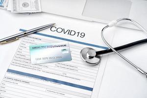 documento di polizza assicurativa coronavirus o covid19 e stetoscopio, tessera sanitaria sulla scrivania, concetto di piano assicurativo sanitario. foto