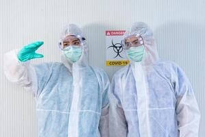 due personale medico asiatico indossano tuta in dpi e guanti medici che mostrano qualcosa nell'aria nella stanza di quarantena foto