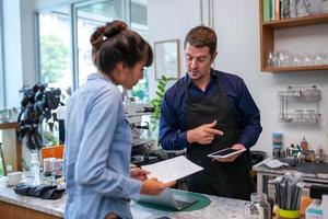 il barista felice prende l'ordine con il tablet dal cliente nella caffetteria. foto