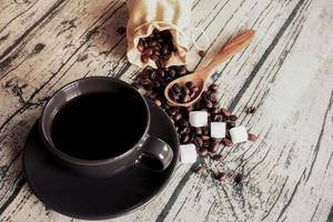 tazza di caffè con i fagioli su un tessuto di lino da tavola in legno. foto