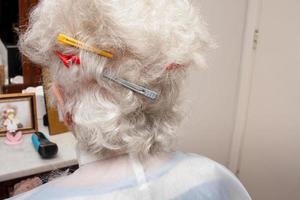 signora anziana che si taglia i capelli nel comfort della sua casa foto