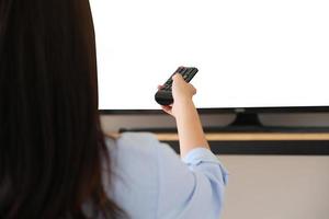 giovane donna con in mano un telecomando per accendere la tv nella nuova era normale in cui non può uscire di casa, lo spazio bianco sulla tv può essere inserito in testo o immagini. foto