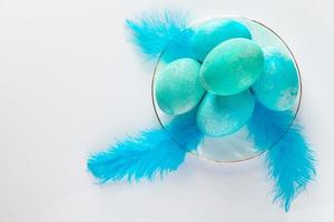 composizione di uova di Pasqua blu e piume su sfondo chiaro. foto