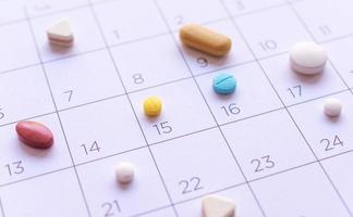 mazzo di pillole diverse su uno sfondo di calendario. concetto di assistenza sanitaria foto