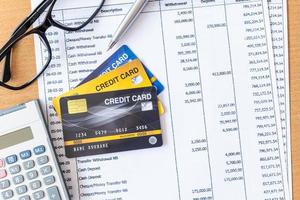 carte di credito e calcolatrice sull'estratto conto bancario su un tavolo di legno foto