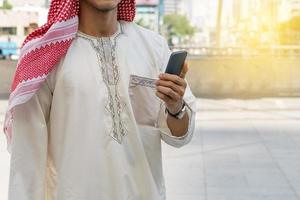 uomo d'affari arabo messaggistica su un telefono cellulare in città foto