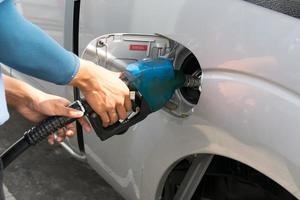 gli uomini tengono l'ugello del carburante per aggiungere carburante in auto alla stazione di servizio foto