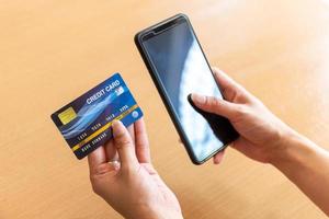 donna in possesso di carta di credito e smartphone. acquisti on-line su internet tramite smartphone foto