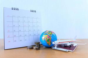 modello di aeroplano con calendario di carta sul tavolo di legno. pianificare il viaggio foto