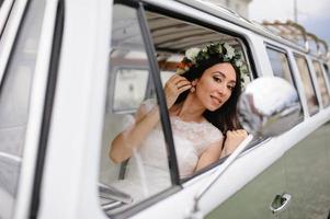 gli sposi hipster sono in piedi vicino al loro autobus retrò. foto