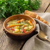 zuppa vegetariana dietetica di verdure primaverili brillante. vista laterale, fondo in legno rustico marrone, tovagliolo di lino. foto