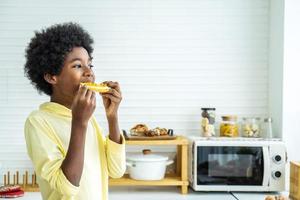 adorabile felice ragazzino che mangia pane tostato con marmellata dolce per colazione in cucina a casa al mattino foto