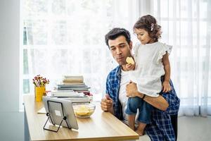 giovane padre attraente e piccola figlia carina che guardano il video del film o il cartone animato sul tablet e mangiano patatine a casa con felicità. foto