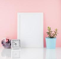 cornice bianca vuota e pianta di cactus, su un tavolo bianco contro il muro rosa con spazio per la copia. mockup con spazio di copia. foto