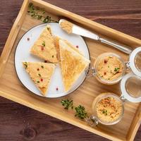 patè di pollo fresco fatto in casa su pane tostato su vassoio su sfondo rustico, vista dall'alto foto