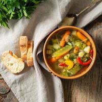 zuppa vegetariana dietetica di verdure primaverili brillante. vista dall'alto, fondo in legno rustico marrone, tovagliolo di lino. foto