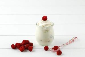 yogurt greco semplice con lamponi, su tavola bianca. foto
