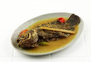 tilapia di pesce pesmol o ikan nila, pesce al curry giallo che si trova spesso nella Giava occidentale, in Indonesia. foto