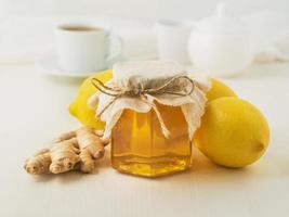 modi popolari per curare un raffreddore: un barattolo di miele, zenzero, limoni su sfondo bianco, vista laterale foto