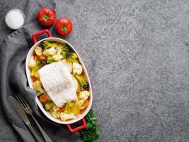 merluzzo di pesce al forno con verdure - dieta sana cibo sano. sfondo in pietra grigia, spazio per la copia, vista dall'alto foto